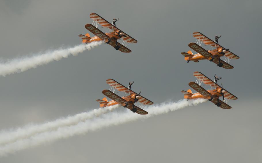 Members of the Breitling Wingwalkers lift their legs while standing atop planes flying over the Farnborough Airshow on July 20, 2014.