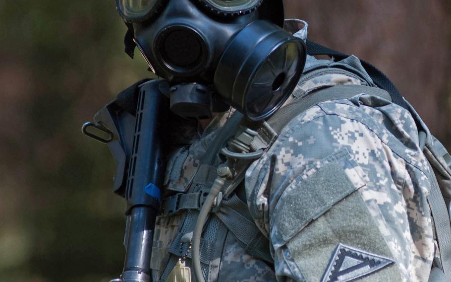 Pvt. Benjamin Ranew, the junior member of the 7th Joint Multinational Training Command's "Best Warrior" team, holds security while other members of his team don gas masks during the competition at Grafenwohr, Germany, Sept. 16, 2014.