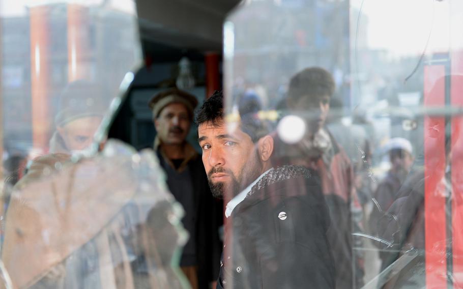 A man looks out a shop window shattered by an attack on a bus carrying Afghan National Army staff. The Jan. 26, 2014, bombing in Kabul killed two ANA employees and two civilians, and wounded at least 22 other people in a busy shopping area along a major road. Civilians are being killed and injured in record numbers in Afghanistan, according to the latest tally by the United Nations.