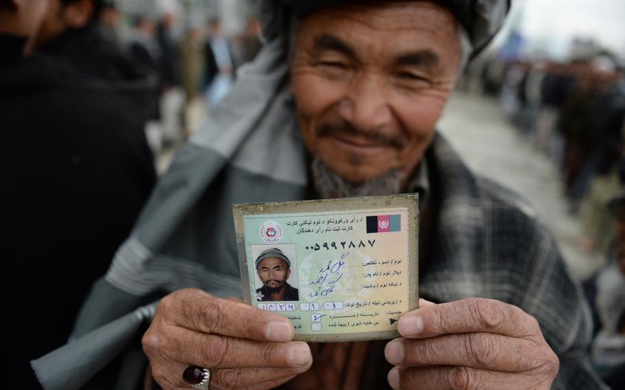 Kabul resident Gul Mohammed displays his voter registration card before voting at a mosque in Kabul during the national elections on April 5, 2014.