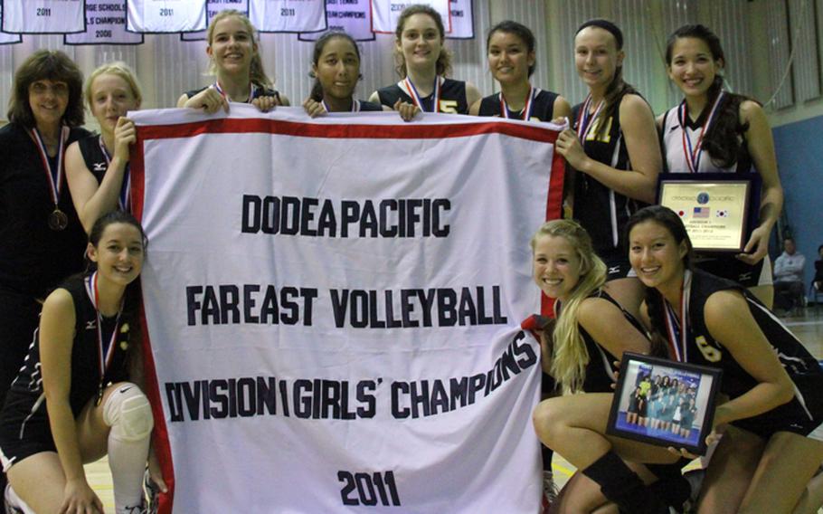 American School In Japan Mustang players celebrate with the banner after Saturday's Far East High School Girls Division I Volleyball Tournament at Yongsan Garrison, South Korea. The Mustangs won their sixth title and third in the last six years, beating Nile C. Kinnick in straight sets.