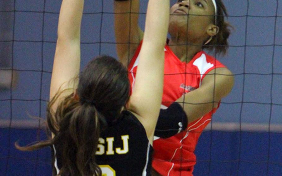 American School In Japan's Elena Wadden tries to block a shot by Nile C. Kinnick's Mashiya McKinney during Saturday's Far East High School Girls Division I Volleyball Tournament at Yongsan Garrison, South Korea. The Mustangs won their sixth title and third in the last six years, beating Kinnick in straight sets.