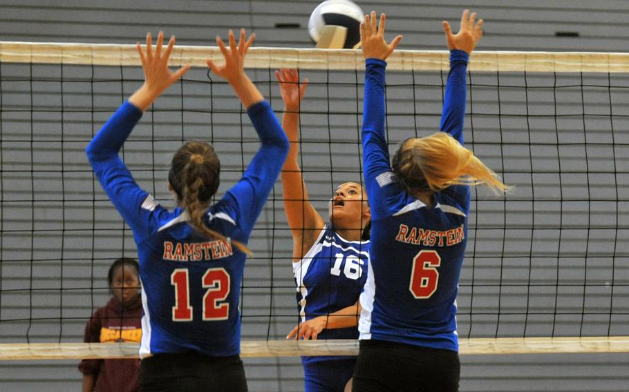 Wiesbaden's Dominique Baldwin gets the ball past the defense of Ramstein's Chera Jensen, left, and Shannon Guffey in volleyball action at Ramstein, Saturday, Sept. 14, 2013. The Warriors  get another shot at Ramstein after taking the season’s opening set from the Royals in the Sept. 14 loss to the defending champs.