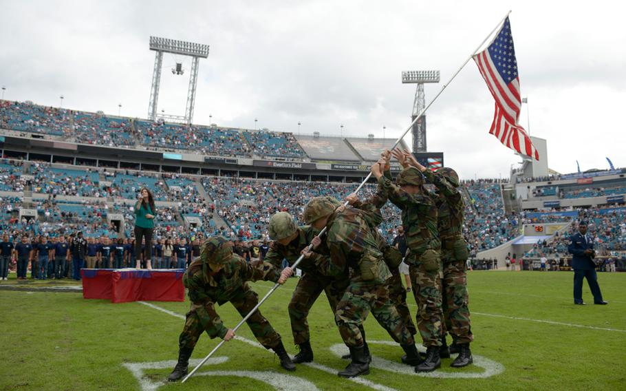 Junior ROTC members perform during a military induction ceremony for new recruits during halftime of an NFL football game between the Jacksonville Jaguars and Arizona Cardinals in Jacksonville, Fla., Sunday, Nov. 17, 2013.