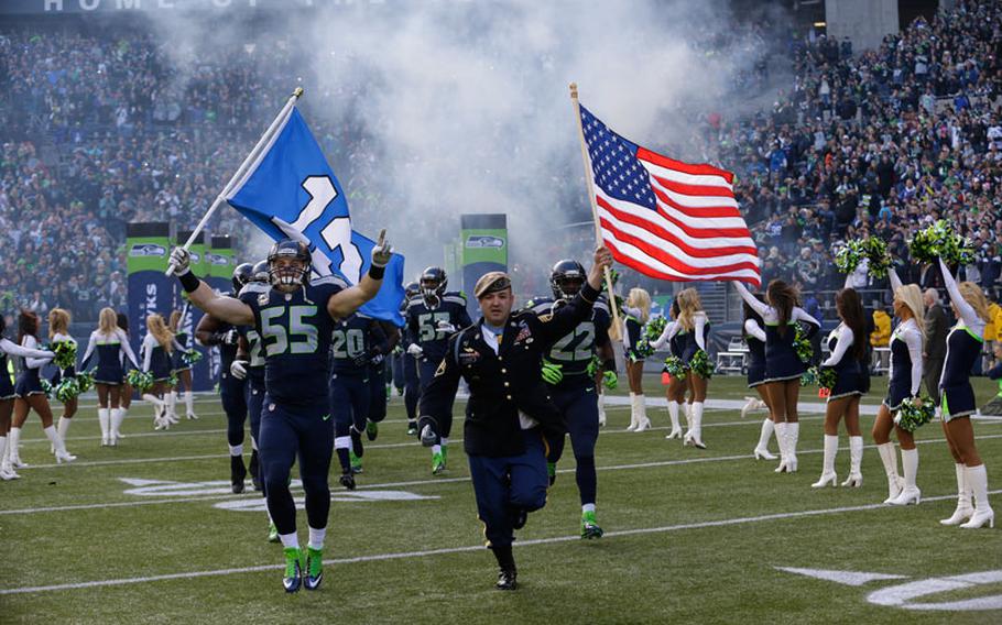 Seattle Seahawks' linebacker Heath Farwell (55) runs with U.S. Army Sergeant First Class and Medal of Honor recipient Leroy Petry, right, as part of the NFL's "Salute to Service" at the start of an NFL football game between the Seattle Seahawks and the Minnesota Vikings, Sunday, Nov. 17, 2013, in Seattle.