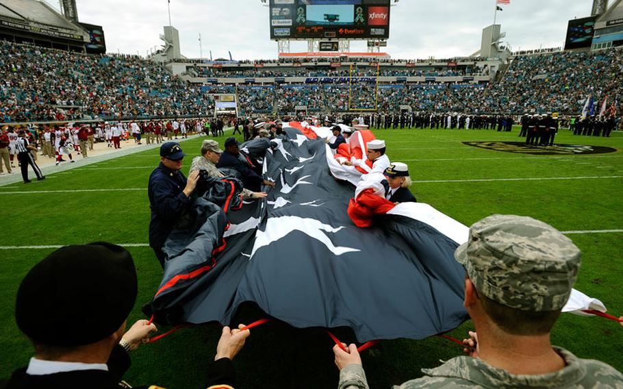 Members of the military gather up a large American flag on EverBank Field before the start of an NFL football game between the Jacksonville Jaguars and Arizona Cardinals, Sunday, Nov. 17, 2013, in Jacksonville, Fla. The Cardinals beat the Jaguars 27-14.