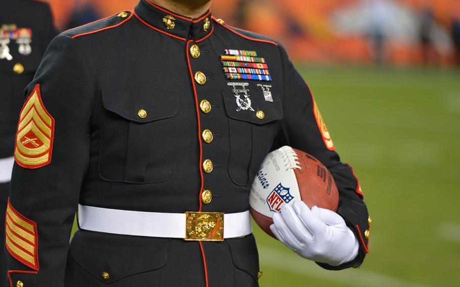 A United States Marine holds an NFL football during a "Salute to Service" tribute at halftime of an NFL football game between the Kansas City Chiefs and the Denver Broncos, Sunday, Nov. 17, 2013, in Denver.