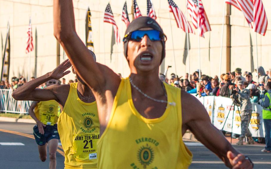 Solonei Da Silva (1) of the Brazilian army crosses the finish line at the Pentagon Sunday morning as the winner of the 2014 Army 10 Miler. Following him across the line are teammates Paulo Roberto Paula (21) and Franck Almeida (18).