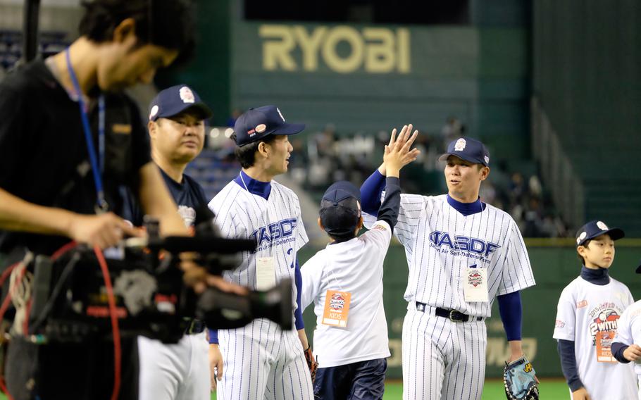 A player from the Japan Air Self-Defense Force team high-fives a young baseball clinic attendee Saturday night, March 21, 2015, at the Tokyo Dome. The clinic was led by former New York Yankees Derek Jeter and Hideki Matsui with volunteers from United States Forces Japan translating.