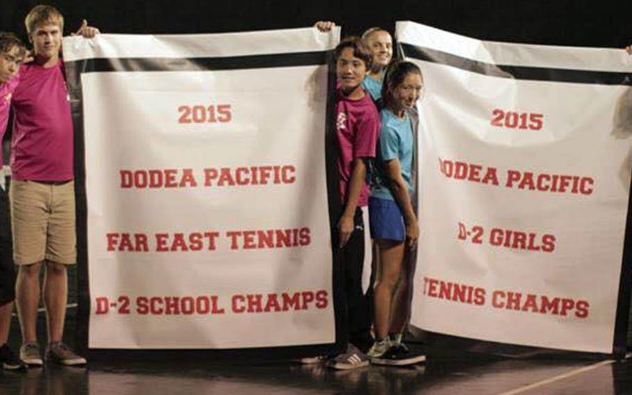 Yokota coaches and tennis players surround their girls and overall school Division II team banners following the Far East High School Tennis Tournament closing ceremonies on Thursday.