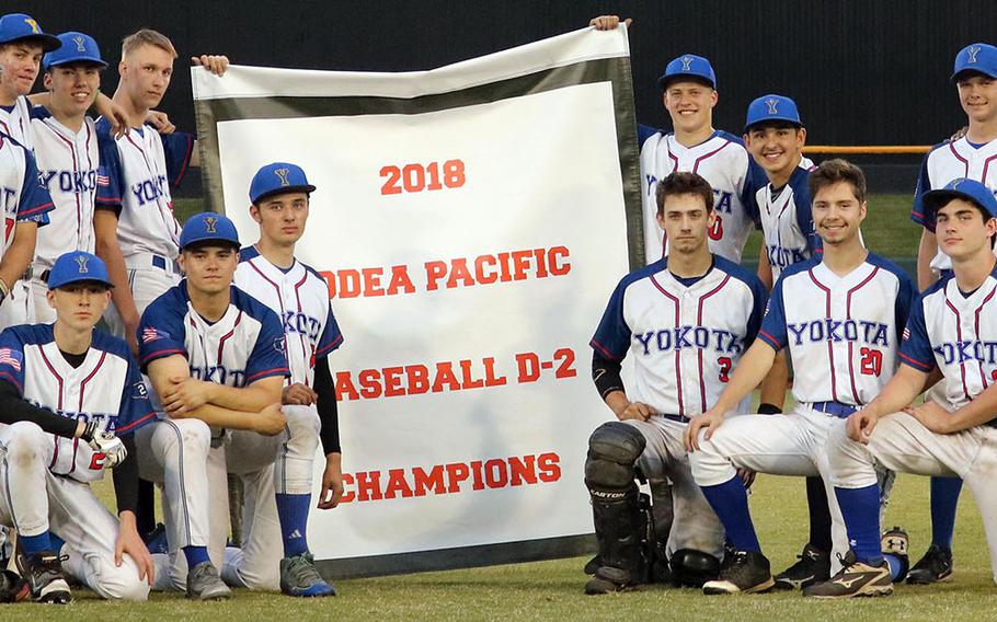 Yokota players and coaches gather round the banner following Tuesday's title game in the Far East Division II baseball tournament. The Panthers routed Zama 14-0.

