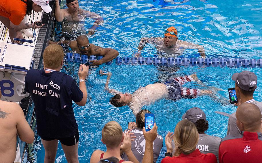 Team SOCOM veteran Capt. James Howard finishes a race in the 2018 DoD Warrior Games swimming competition surrounded by supporters and competitors in the race at the Air Force Academy in Colorado Springs, Colo. June 8, 2018.