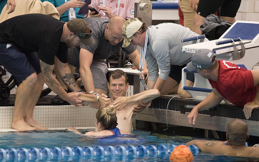 SOCOM veteran Capt. James Howard is helped from the pool after swimming in the 100 meter freestyle event during the 2018 DoD Warrior Games at the U.S. Air Force Academy in Colorado Springs on June 8, 2018.  Howard, a quadriplegic, earned a gold medal in his category.