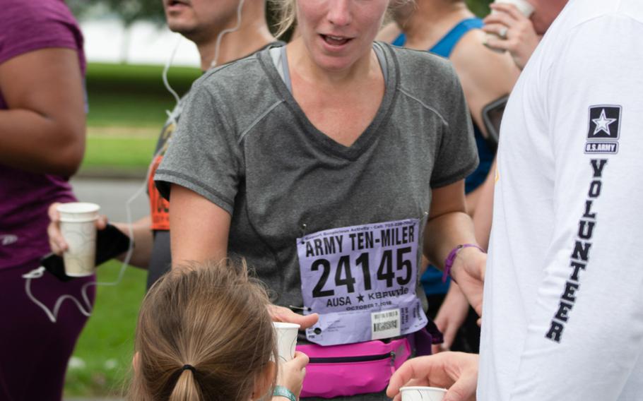 Runners pause for a cup of water shortly after the Mile 4 marker during the Army Ten-Miler on October 7, 2018. 