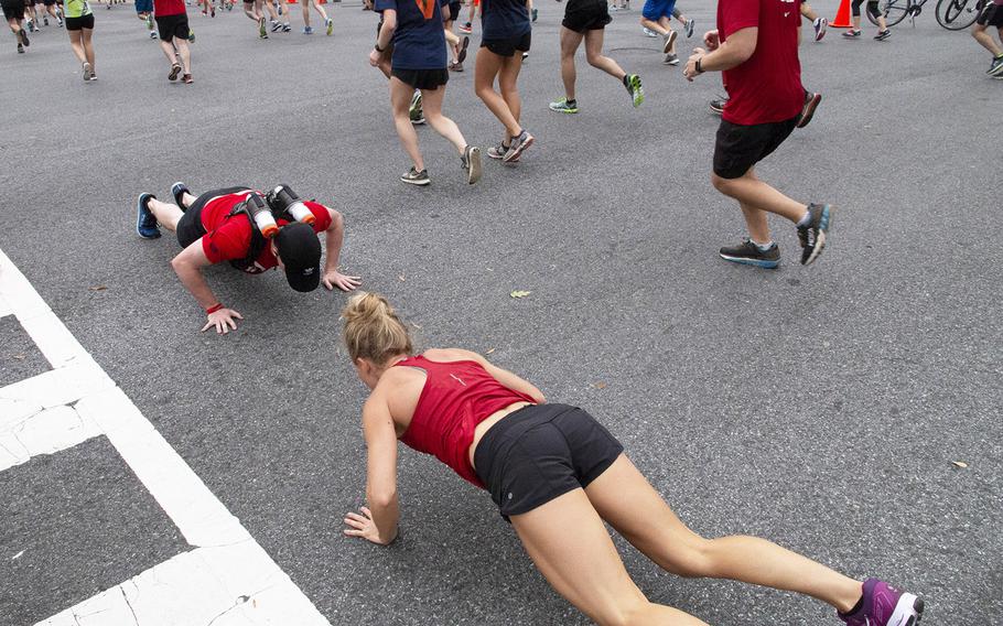 Devin Ruic of Arlington, Va., left, running for Team Red, White and Blue, stops to do some pushups with Gretchen Apgar during the Army Ten-Miler in Washington, D.C., Oct. 7, 2018.