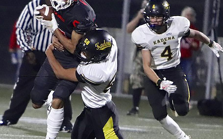 Kinnick receiver Chris Watson tries to elude Kadena defenders Noah Ricafrente and Christian Tsirlis.