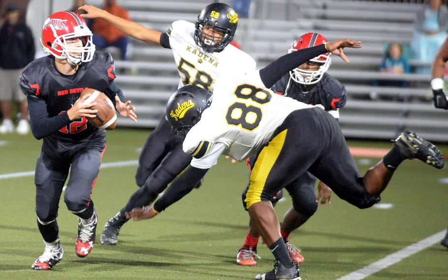 Kinnick quarterback Patrick Kelly tries to evade Kadena defenders Noah Ricafrente and Jalen McCants.