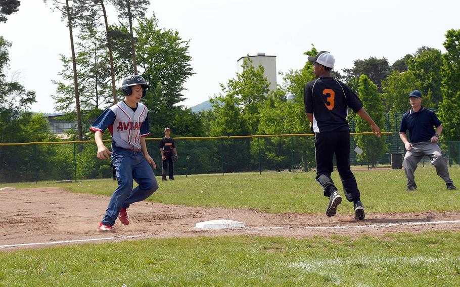 Aviano's David Hannaford approaches third base as Spangdahlem's Eddie Dejesus watches the action on Saturday, May 25, 2019, in the DODEA-Europe Division II title game.