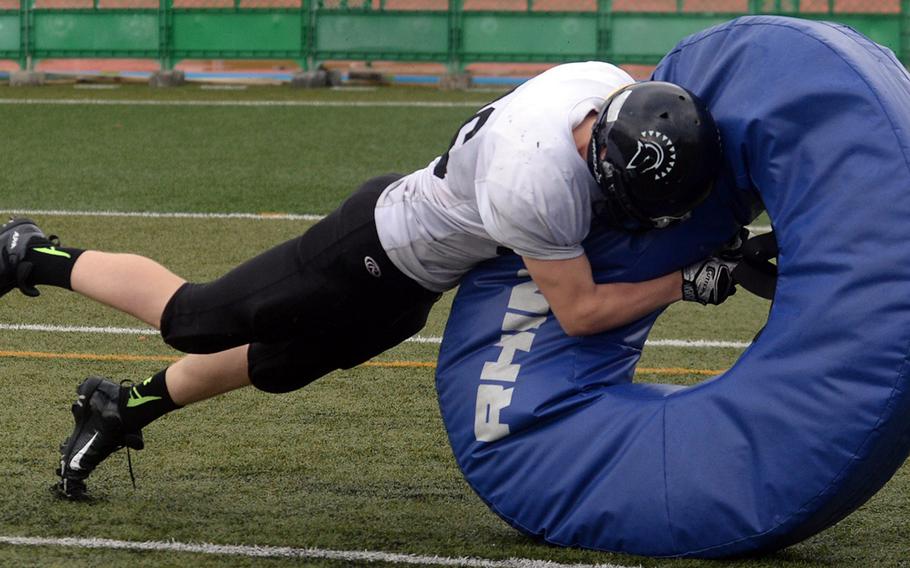 Junior Joshua Reilly gives the tackling tire a whack during Zama football practice. His father, Marine Corps Col. Michael D. Reilly, is Camp Fuji's commanding officer.