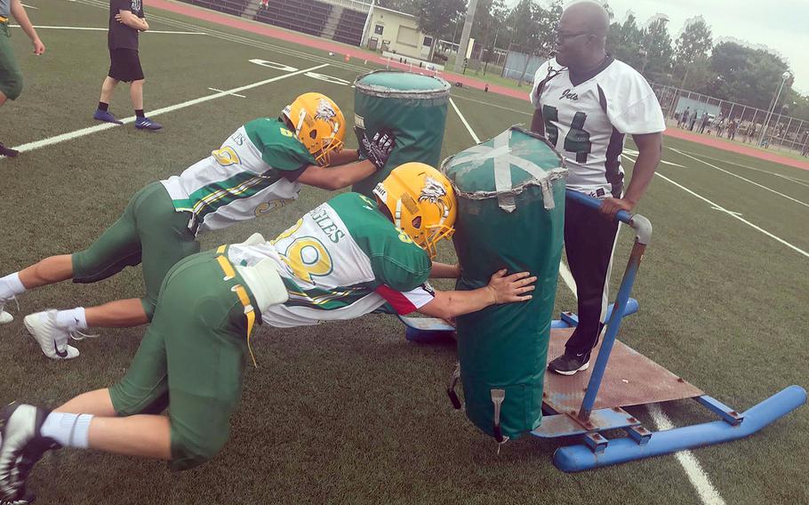 Edgren coach Jeremy Sanders works with two players on the blocking sled.