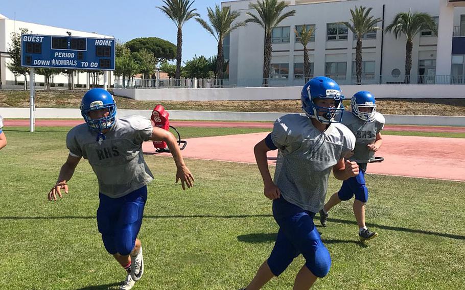 Rota football players Wes Penta, Bodie Escanes and Michael Caprio run off the field after completing a drill at a preseason practice session at Naval Station Rota, Spain.