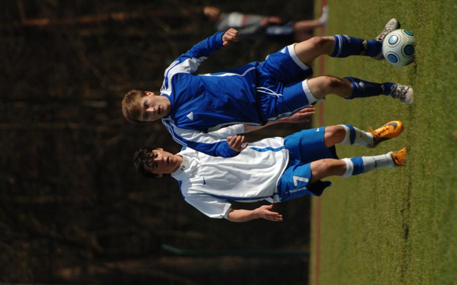 Ramstein’s Dylan Sharpy looks to pass the ball as International School of Brussels midfielder Alessandro Pryce approaches from behind Friday during the Royals’ 3-1 loss to visiting ISB. 