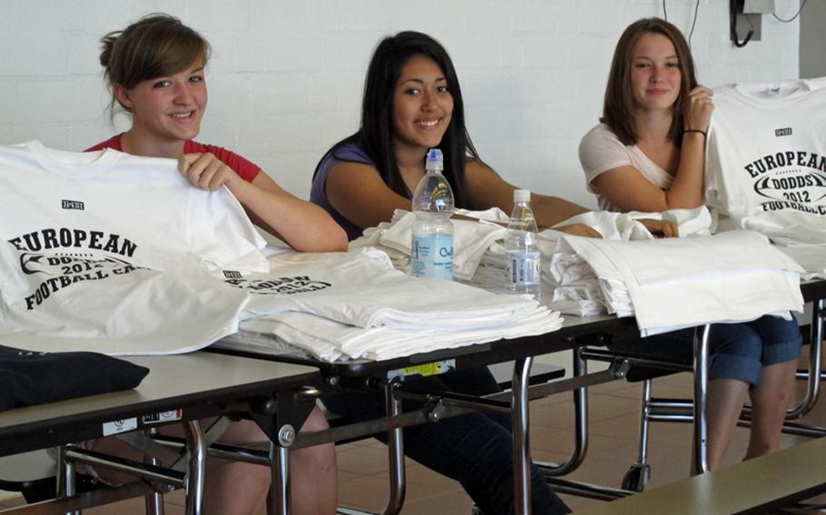 Volunteers from Ansbach High School hand out T-shirts Aug. 11, 2012, during registration for the annual DODDS-Europe football camp. From left are sophomore Christina Miller and juniors Vianey Ramirez and Brittany Julian.