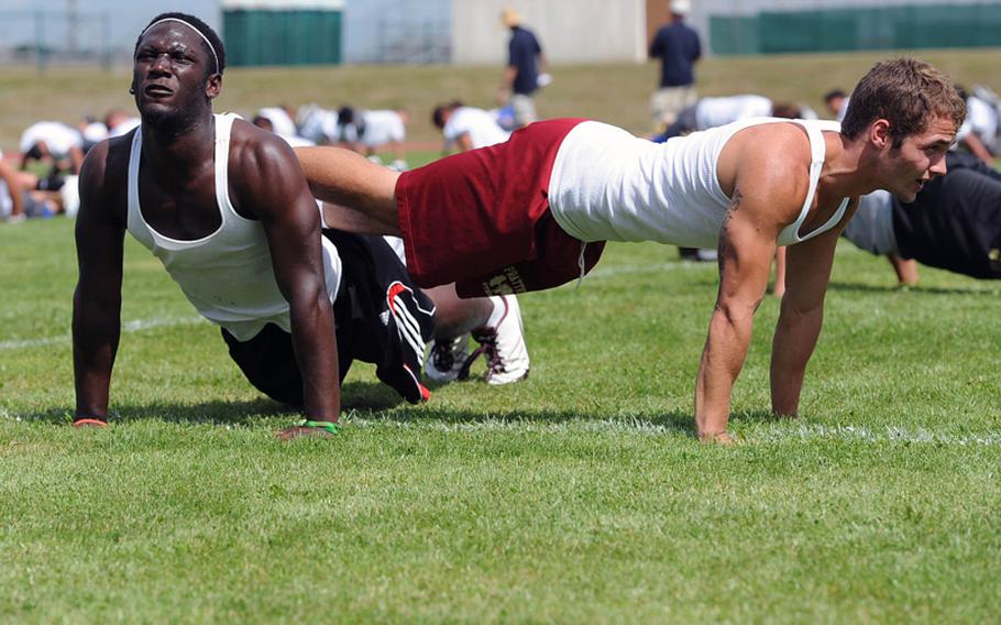 Vilseck's Shawn Peebles, left, and Blade Stauss do pushups as they warm up for an afternoon session at the DODDS European Football Camp in Ansbach, Germany, on Aug. 13, 2012.