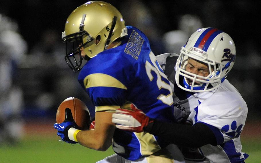 Wiesbaden's Justin Gershen picks up yardage despite the defense of Ramstein's Matthew Sharpy. Despite Gershen's  efforts here, the Warriors fell to the Royals 14-0 at home Friday night.
