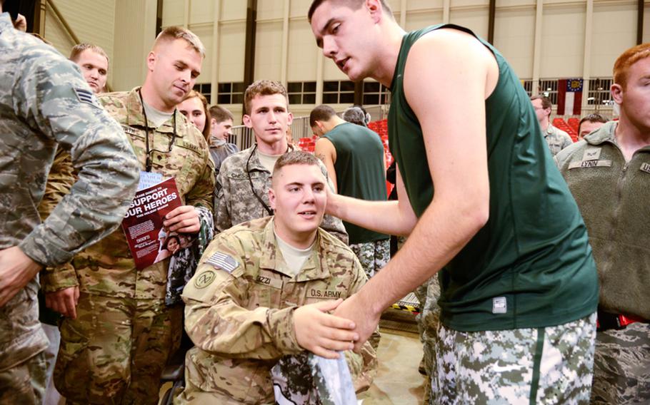 U.S. Army Spc. Cory Gizzi, a wounded warrior with the 27th Maintenance Brigade, receives a jersey from Michigan State's Kenny Kaminski Friday night after Connecticut upset Michigan State in the Armed Forces Classic at Ramstein Air Base, Germany.