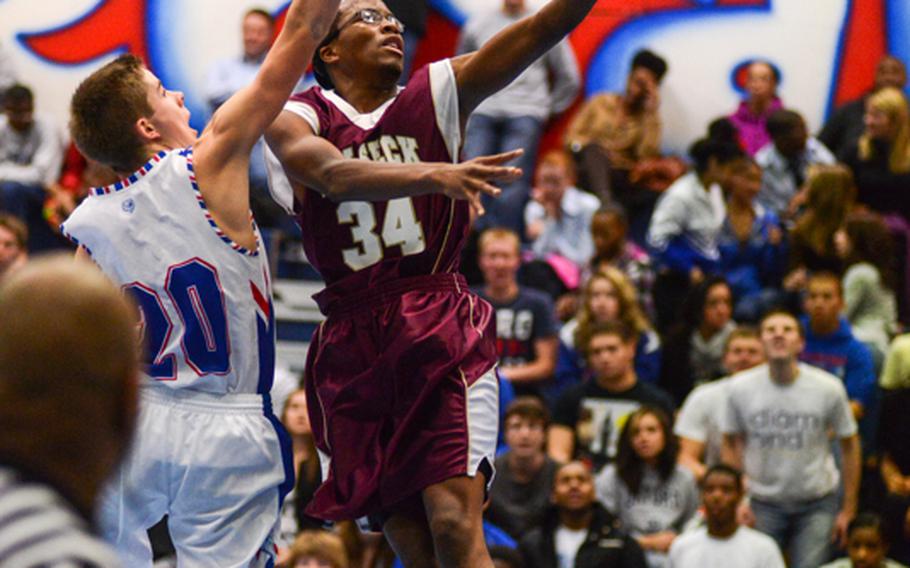 Vilseck High School's John Kiner protects the ball for a layup ahead of Ramstein High School's Kevin Tarnowski Friday night as the Royals defeated the visiting Falcons.