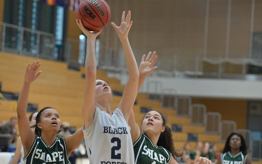 Black Forest Academy's Emily Campbell puts back up a rebound against SHAPE's Maxine White, left, and Ryan Paine in a Division II semifinal at the DODDS-Europe basketball championships in Wiesbaden, Germany, Friday Feb. 21, 2014. BFA won 36-18 to advance to Saturday's final. 

