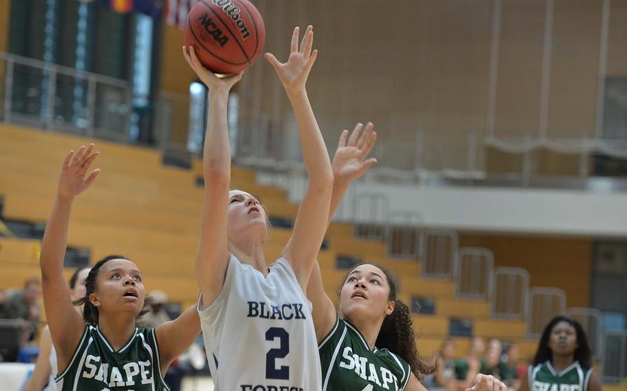 Black Forest Academy's Emily Campbell puts back up a rebound against SHAPE's Maxine White, left, and Ryan Paine in a Division II semifinal at the DODDS-Europe basketball championships in Wiesbaden, Germany, Friday Feb. 21, 2014. BFA won 36-18 to advance to Saturday's final.
