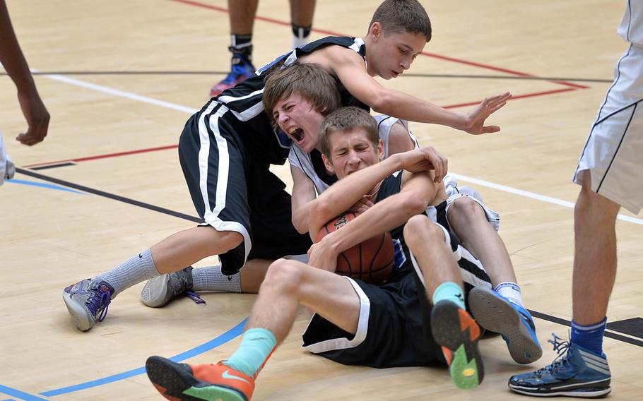 Tim Wilkinson of Brussels gets squeezed between Incirlik's Patrick Ostrand, foreground, and Blake Bass as they fight for a loose ball in the Division III final at the DODDS-Europe basketball championships in Wiesbaden, Germany, Saturday, Feb. 22, 2014. Brussels won 41-33 to take the title.