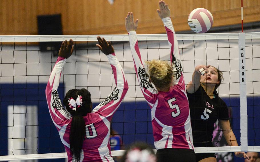 Ramstein's Montgomery Sauter spikes the ball past Vilseck's Amanda Seay, middle, and Mahogany Lediju, left, Saturday, Oct. 4, 2014 during a volleyball match at Ramstein, Germany.