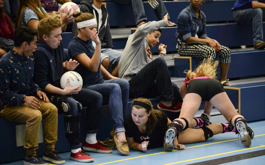 Ramstein's Montgomery Sauter, on the floor, and Natalie Sell surprise a few spectators after hustling for the ball Saturday, Oct. 4, 2014 during a volleyball match against Vilseck at Ramstein, Germany.