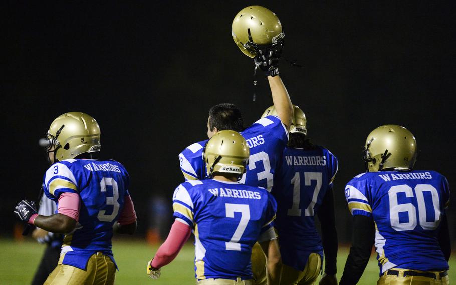 Wiesbaden's Hunter Lunasin holds his helmet up to celebrate a 20-14 overtime win against Ramstein at Wiesbaden, Germany on Friday, Oct. 10, 2014.