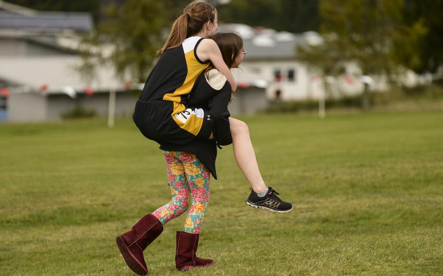 Vicenza's Nicole McCollaum gets a piggy-back ride from her 12-year-old sister, Rachel McCollaum, after finishing the DODDS-Europe cross country championship race at the Rolling Hills Golf Club in Baumholder, Germany, Saturday, Oct. 25, 2014.