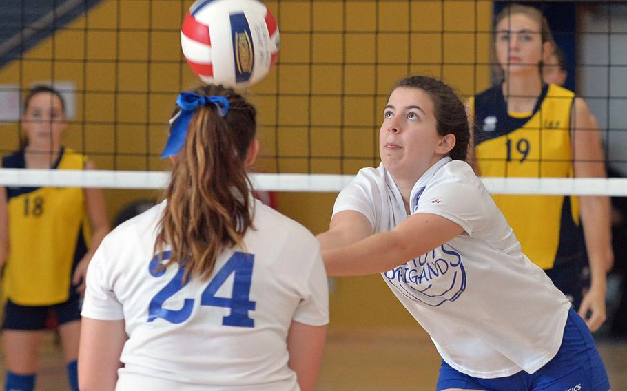 Brussels' Juliette Mobley, right, sets the ball for a teammate as sister Sarah watches, in a Division III match against Florence at the DODDS-Europe volleyball championships in Ramstein, Germany, Friday Oct. 31, 2014. Florence won 25-18, 25-16. Following the action in the background are Anna Pacciani, left, and Margarita Reznichenko.