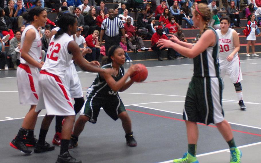 Kaiserslautern's Morgan Dozier, right, and Andrea Fresch defend against SHAPE's Milagro Hill in the Raiders' 35-18 win over the SHAPE Spartans on Friday, Dec. 12, 2014, at Kaiserslautern High School.
