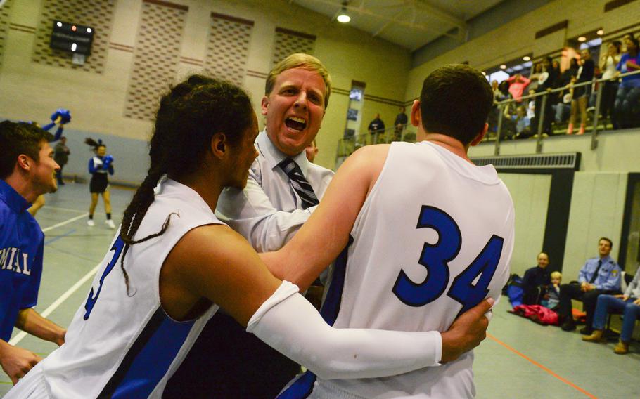 Rota's head coach, Ben Anderson, celebrates with his players after his team defeated AOSR in overtime to clinch a spot in Friday's semi-finals in the second day of DODDS-Europe tournament play, Thursday, Feb. 19, 2015.