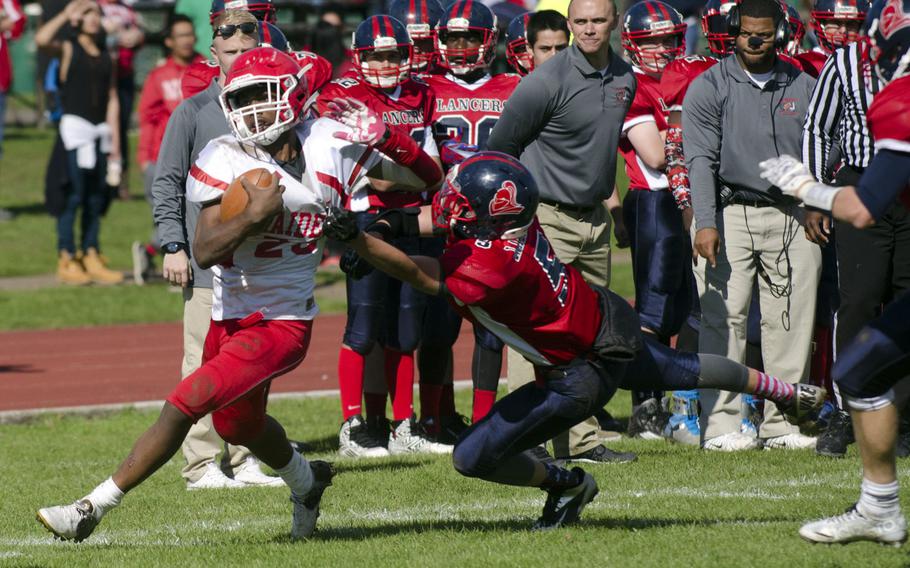 Kaiserslautern's Jamarkus Myles rushes while Lakenheath's Riley Palmer clings to him during a game at RAF Lakenheath, England, on Saturday, Sept. 19, 2015. Myles scored one touchdown during the game.
