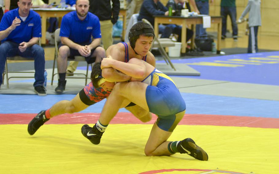 Wiesbaden's Zach Krapf, in blue and gold, struggles against Ramstein's Chad Chason in the 160-pound division final matchup Saturday at Wiesbaden. Krapf defeated Chason to take first place in the division.
