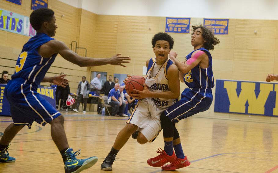 Isiah Washington of Wiesbaden drives past two Ansbach players in a boys basketball game Friday, Jan. 8, 2016 in Wiesbaden. The hosts defeated the visiting Cougars 76-37 on the back of a 20-3 surge to open the second half.