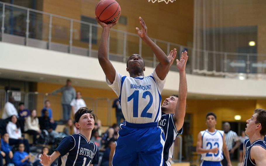 Marymount's Lotanna Mba gets past Bitburg defenders Eli Canaan, left, and Alexander Rodriguez in opening-day Division II action at the DODDS-Europe basketball championships in Wiesbaden, Germany, Wednesday, Feb. 24, 2016. Marymount won 44-39.
