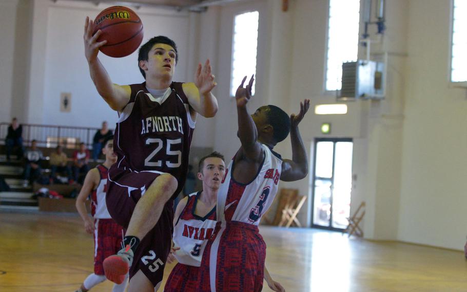 AFNORTH's Logan Harless drives to the basket against Aviano's Aaron Island in a Division II game at the DODDS-Europe basketball championships in Wackernheim, Germany. The Saints beat the Lions 53-34. 
