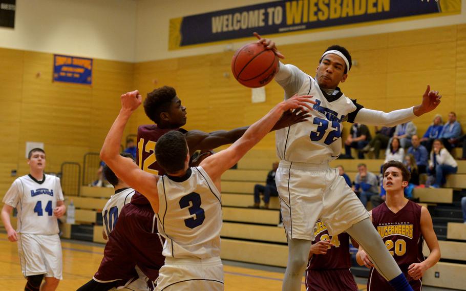 Brussels' Paul Hubbard blocks a shot by Baumholder's Nathaniel Horton in a Division III game at the DODDS-Europe basketball championships in Wiesbaden, Germany, Thursday, Feb. 25, 2016.Brussels beat the Bucs 29-24. Helping out in the foreground is Brussels’ Michael DeFazio.