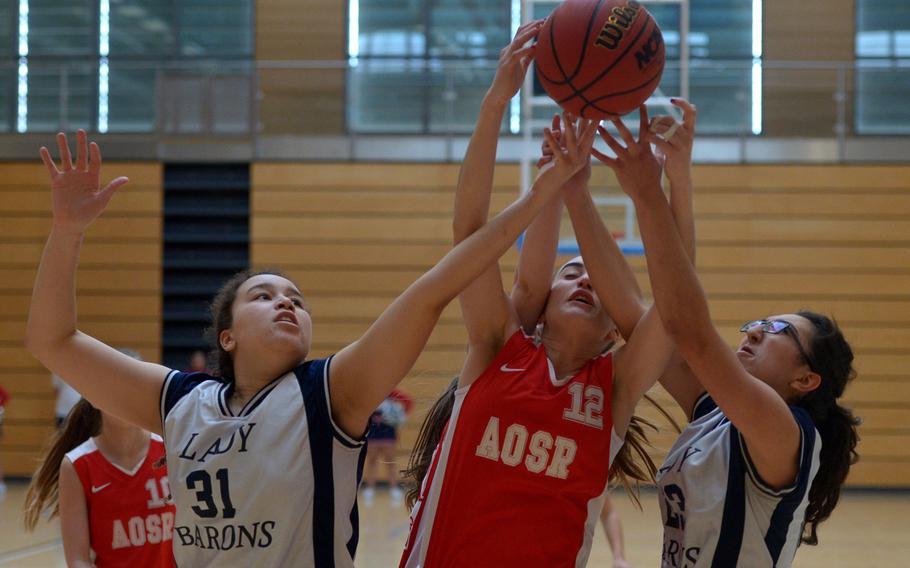 Bitburg's Elise Rasmussen, left, and Victoria Porras fight AOSR's Nicole Bensaia for a rebound  in a Division II game at the DODDS-Europe basketball championships in Wiesbaden, Germany, Thursday, Feb. 25, 2016. Bitburg won the game 43-18.