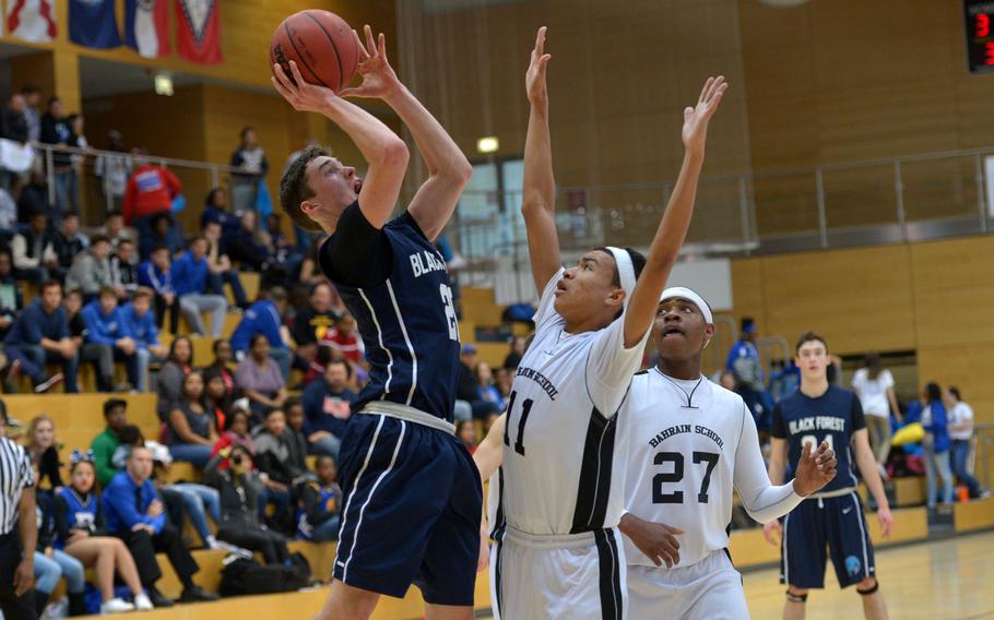 Black Forest Academy's Noah Greathouse shoots over Bahrain's Ethan Peterman as teammate Jaelin Wright watches the action in a Division II semifinal at the DODDS-Europe basketball championships in WIesbaden, Germany. Friday, Feb. 26, 2016. BFA defeated Bahrain 52-50 to advance to Saturday's final against Rota.