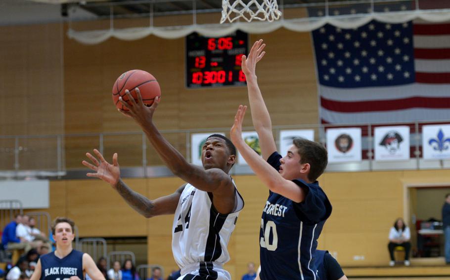 Bahrain's Rashay Douglas, left, scores a basket against Black Forest Academy's Jason Kragt in a Division II semifinal at the DODDS-Europe basketball championships in WIesbaden, Germany. Friday, Feb. 26, 2016. BFA defeated Bahrain 52-50 to advance to Saturday's final against Rota.